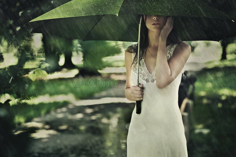 Junge attraktive Frau mit grünen Regenschirm im Regen.