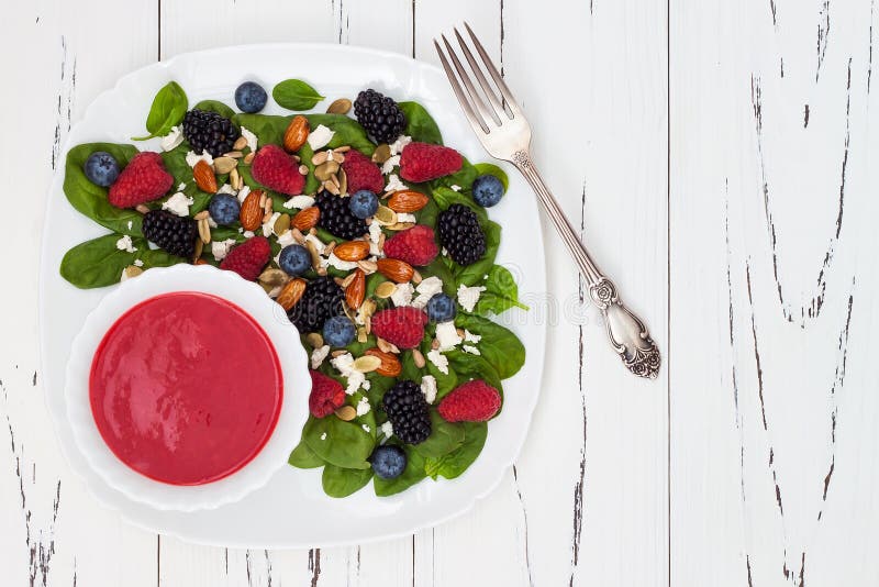 Summer refreshing spinach mixed berry salad with pumpkin and sunflower seeds, almonds, feta cheese and red raspberry vinaigrette