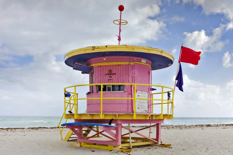 Summer scene with a colorful lifeguard house in a typical landmark Art Deco style in Miami Beach, Florida with blue sky and ocean in the background. Summer scene with a colorful lifeguard house in a typical landmark Art Deco style in Miami Beach, Florida with blue sky and ocean in the background.