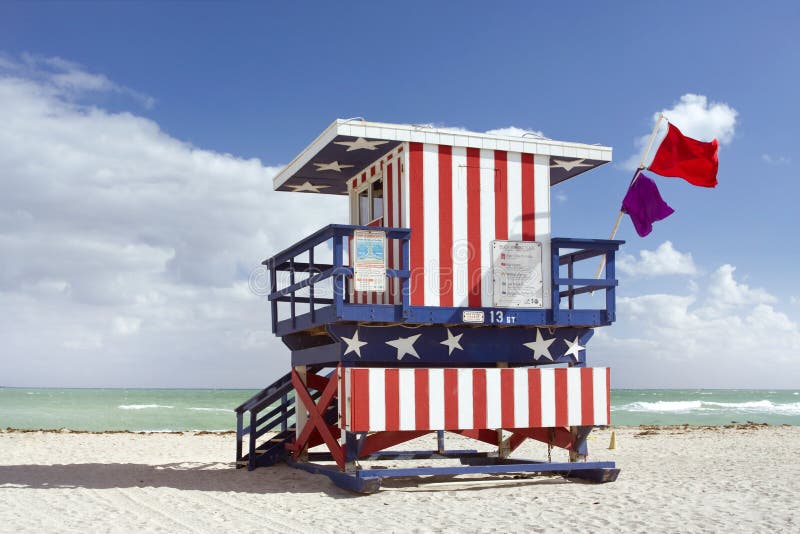 Summer scene with a lifeguard house in Miami Beach, Florida in the colors of the American flag with blue sky and ocean in the background. Back view.