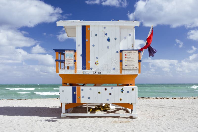 Summer scene with a colorful lifeguard house in a typical landmark Art Deco style in Miami Beach, Florida with blue sky and ocean in the background. Summer scene with a colorful lifeguard house in a typical landmark Art Deco style in Miami Beach, Florida with blue sky and ocean in the background.