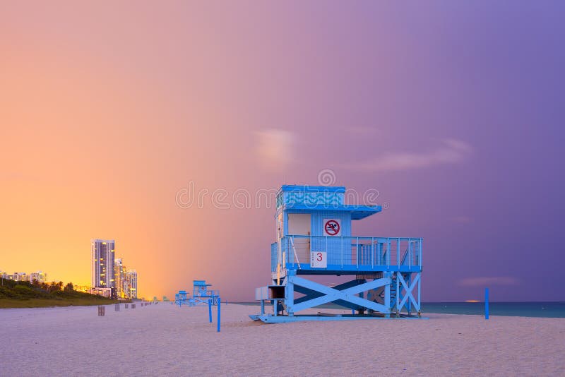 Summer scene in Miami Beach Florida, with a blue lifeguard house in a typical Art Deco architecture, at sunset with ocean and colorful sky in the background