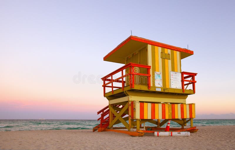 Summer scene in Miami Beach Florida, with a colorful lifeguard house in a typical Art Deco architecture, at sunset with ocean and sky in the background. Summer scene in Miami Beach Florida, with a colorful lifeguard house in a typical Art Deco architecture, at sunset with ocean and sky in the background.