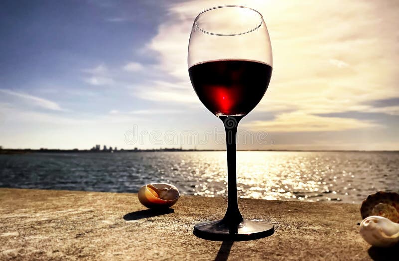 Summer seaside glass of red wine on beach stone and seashells nature panorama blue sky and sea water sunlight reflection romantic  background skyline on horizon Tallinn old town