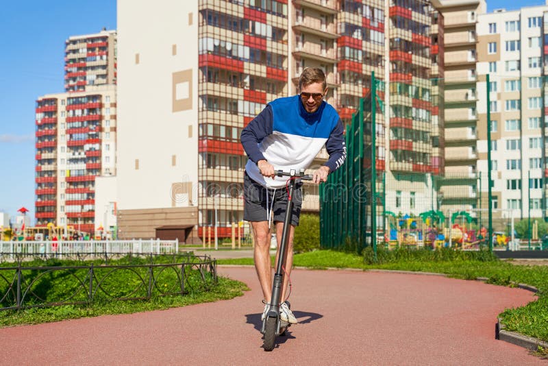 Joyful trendy athletic guy drives eco scooter. stock photos Joyful trendy athletic guy drives eco scooter. stock photos