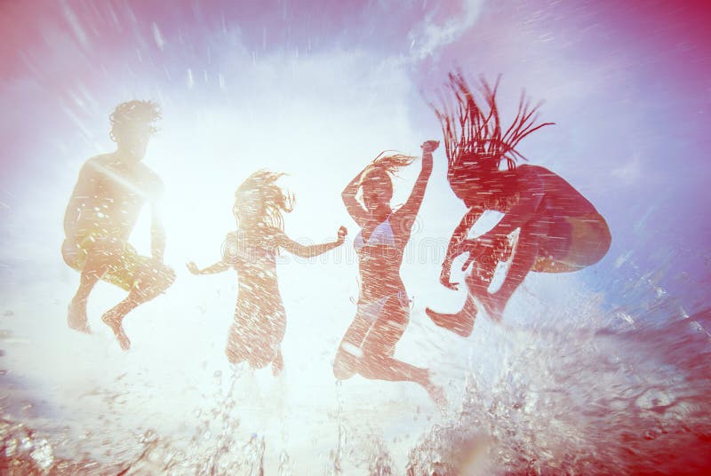 Summer silhouettes of happy young people jumping in sea on the beach. vintage retro style with soft focus and sun flare