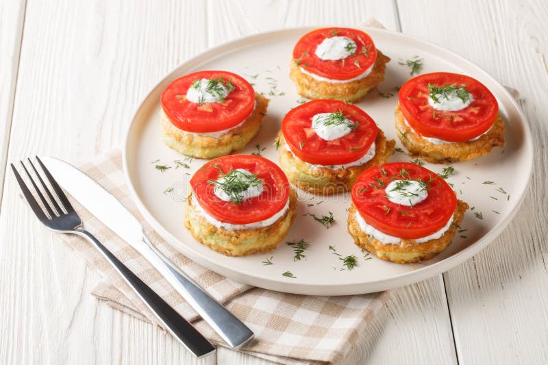 Summer snack of zucchini in egg batter with creamy garlic sauce and fresh tomatoes close-up in a plate. Horizontal