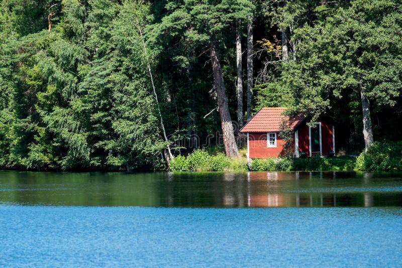 Typical red little cottage by a lake in Sweden at summertime. Typical red little cottage by a lake in Sweden at summertime