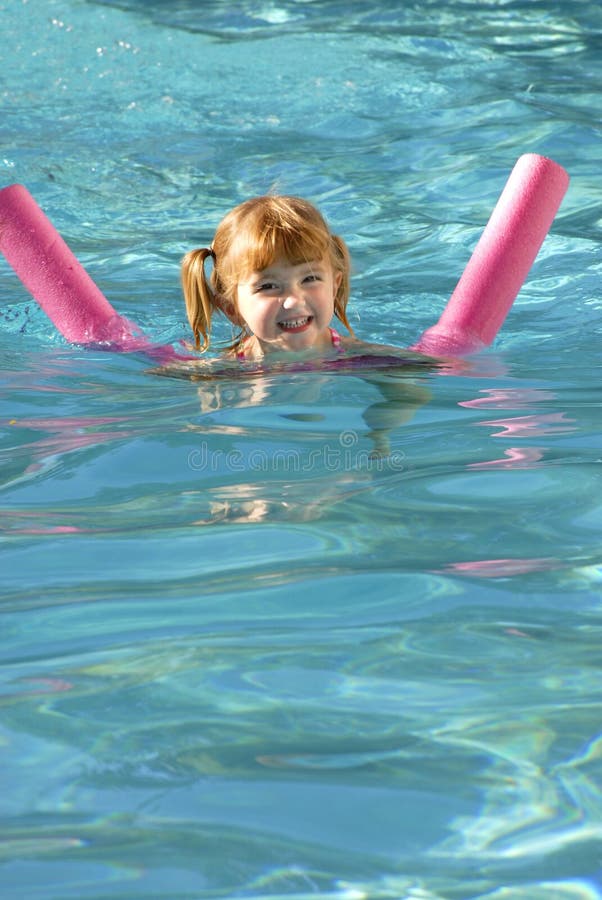 Young girl swimming in a swimming pool with floating device. Young girl swimming in a swimming pool with floating device