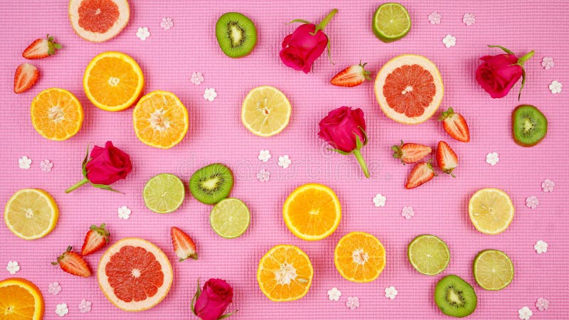 Summer theme background with fruit, citrus and flowers on pink backdrop.