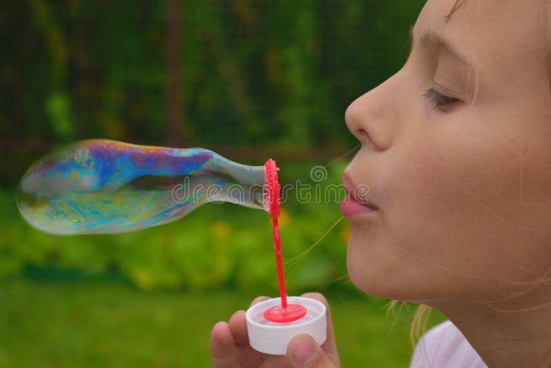 Beautiful girl inflates soap bubbles. Cheerful happy action at the child. royalty free stock images Beautiful girl inflates soap bubbles. Cheerful happy action at the child. royalty free stock images