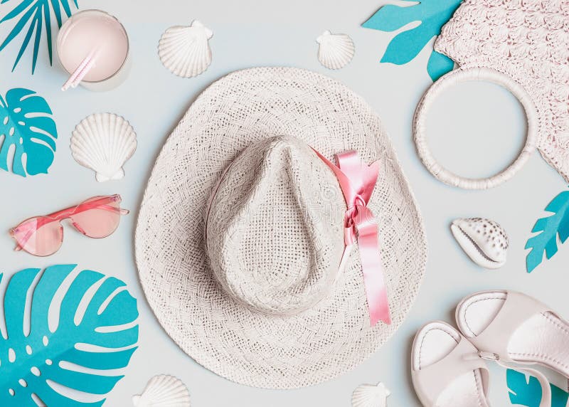 Summer woman accessories with  shells and tropical leaves on pastel color background, top view. Straw hat, sunglasses, sandals and