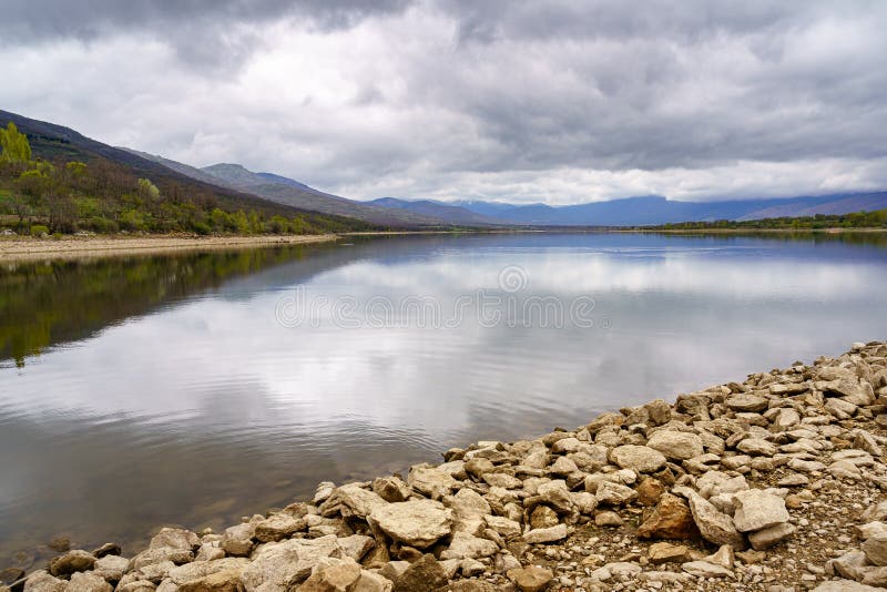 Sumpflandschaft mit Reflexionen im Wasser der Berge und Ufer mit großen rustikalen Steinen lizenzfreies stockfoto