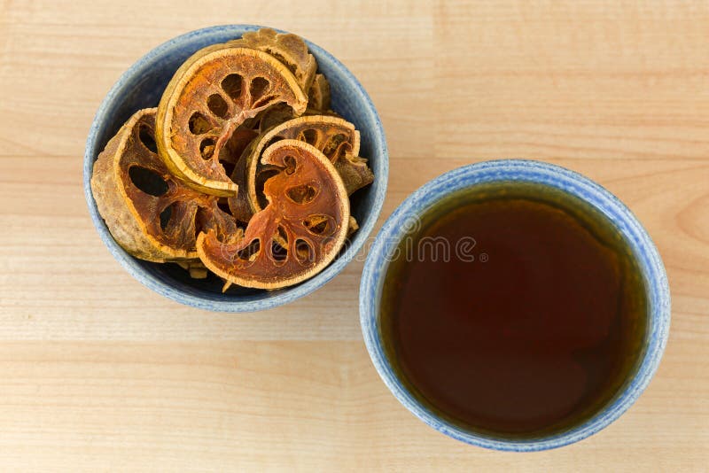 Sun Dried Bael Fruit in bowl next to cup of hot Bael herbal tea, also called Stone Apple