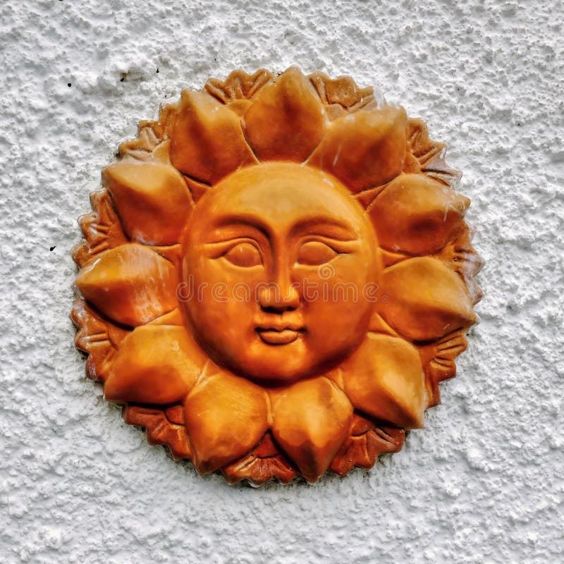 Handmade terracotta sun face on the wall stock image.