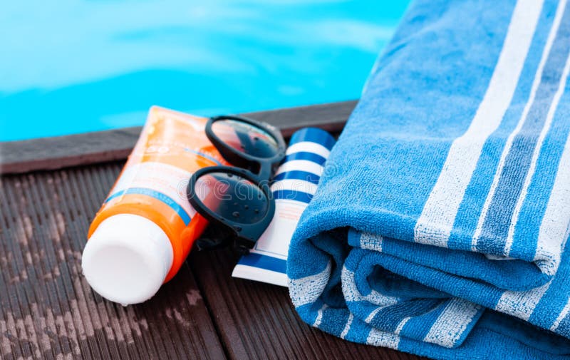 Sun Glasses, Tube of Sunscreen Cream, Blue Towel Near Swimming Pool ...