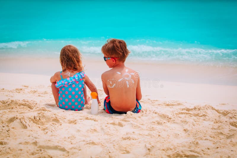 Sun protection- little boy and girl with suncream at beach