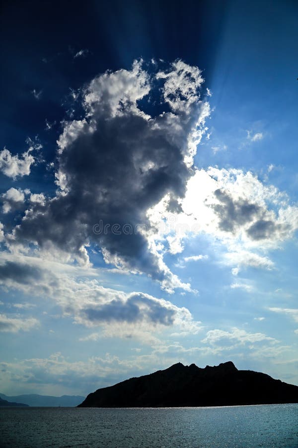 Sun rays piercing through clouds over the volcanic island of Savo, Solomon Islands royalty free stock photos