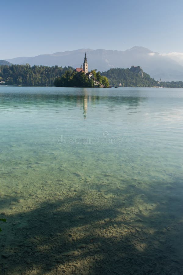 The sun rises above Lake Bled on a clear day. The mountains are visible behind the church on the island royalty free stock photography The sun rises above Lake Bled on a clear day. The mountains are visible behind the church on the island royalty free stock photography