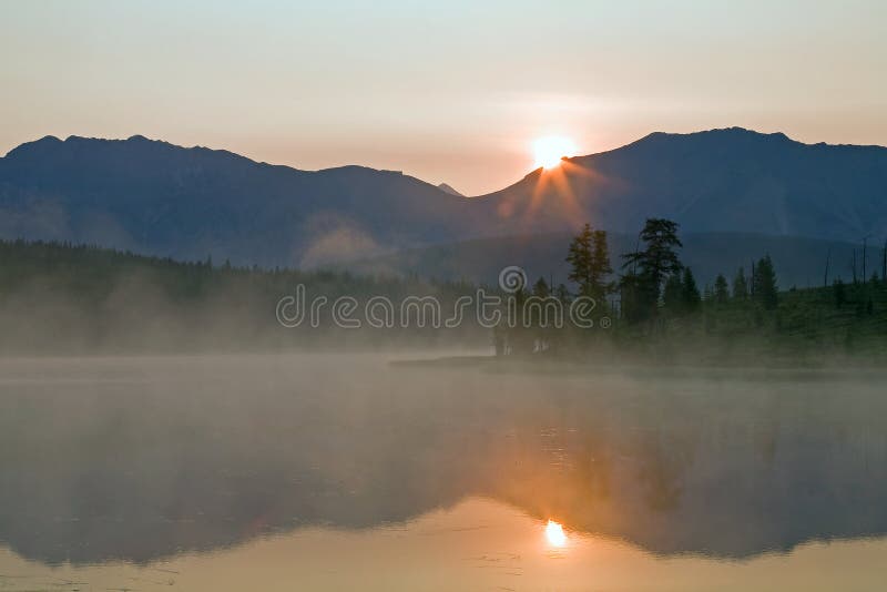 The sun rising over the mountain and the reflection in the lake.
