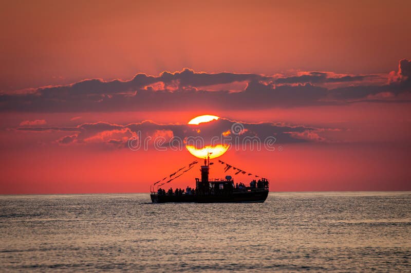 Sun setting behind a boat sailing on the ocean