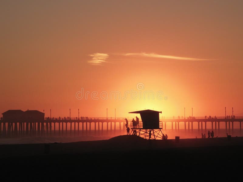 The Sun Setting Behind a Lifeguard Tower with the Silhouettes of ...