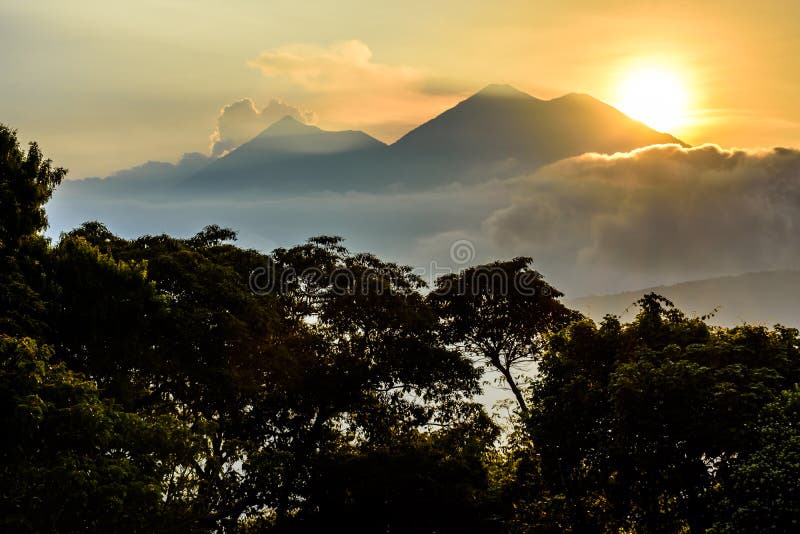 Sun setting over Fuego volcano & Acatenango volcano near Spanish colonial town & UNESCO World Heritage Site of Antigua, Guatemala, Central America
