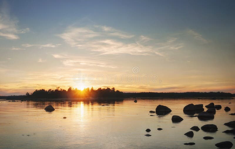 Sun sits down behid island. Beautiful sunset, reflecting in water.  Clean nordic nature, Baltic sea, gulf of Finland