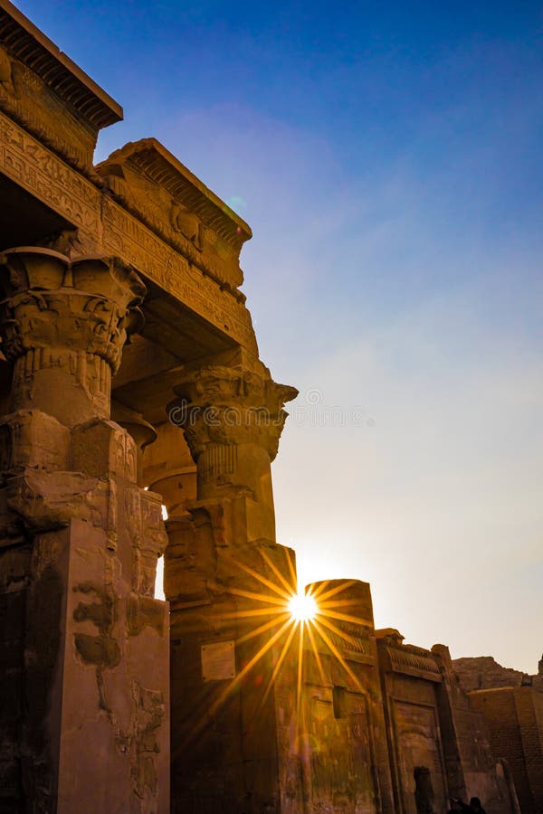 Sun starburst peaks between hieroglypic carvings at the entrance to ancient tempp0le of Kom Ombo