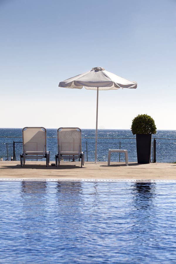 Sun umbrella and chairs near a pool royalty free stock images