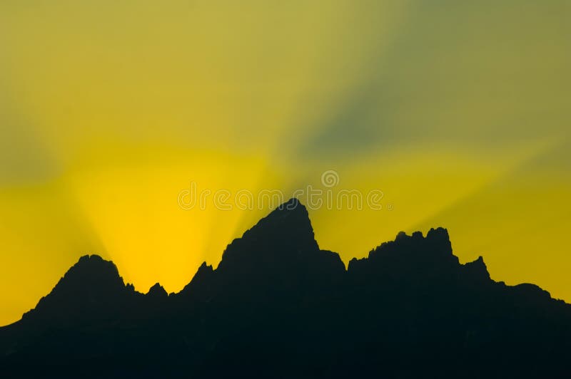 Sunbeams burst over mountains at sunset