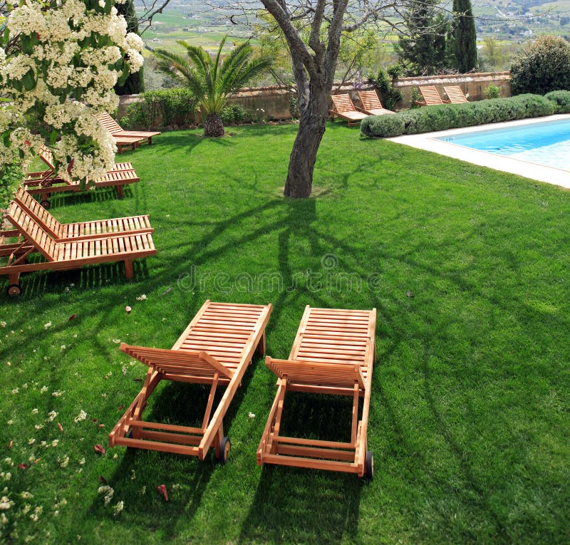 Sunbeds vicino ad una piscina in giardino immagini stock libere da diritti