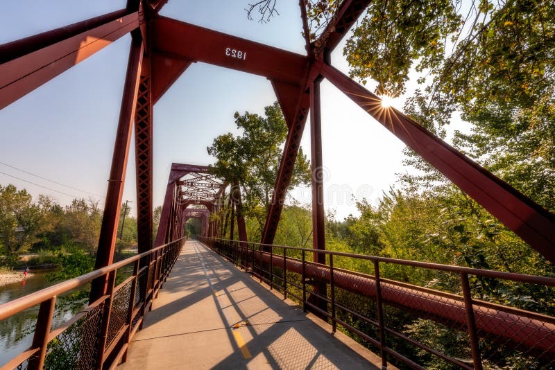 Sunburst flairs across a unique footbridge at the Boise River