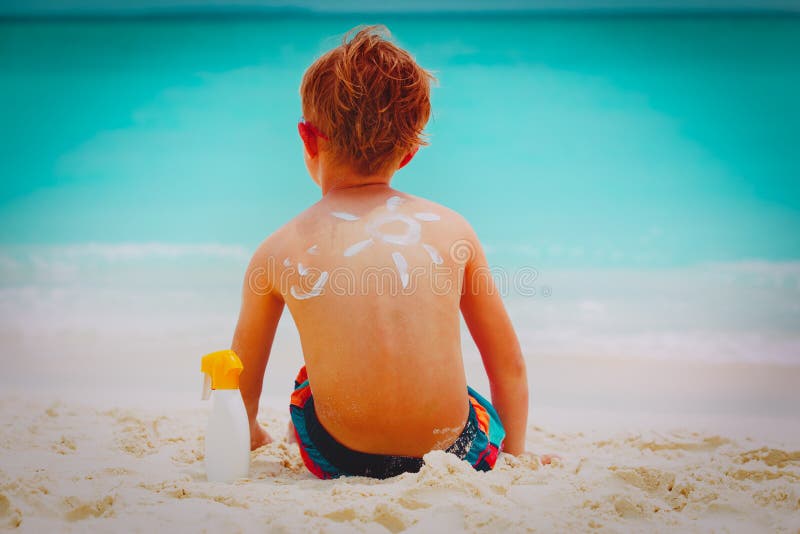 Μικρό παιδί προστασίας ήλιων με το suncream στην παραλία στοκ φωτογραφίες