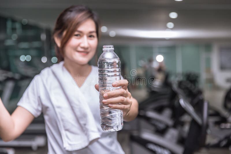 Sund asiatisk flaska för show för kvinnahandhåll av drinkvatten med sportklubban arkivbilder Sund asiatisk flaska för show för kvinnahandhåll av drinkvatten med sportklubban arkivbilder