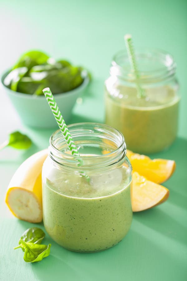 Sund grön smoothie med spenatmangobananen i glass krus royaltyfria bilder Sund grön smoothie med spenatmangobananen i glass krus royaltyfria bilder
