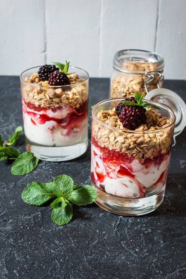 Sund i lager efterrätt med yoghurten, granola, driftstopp, björnbär i exponeringsglas på stenbakgrund royaltyfri bild Sund i lager efterrätt med yoghurten, granola, driftstopp, björnbär i exponeringsglas på stenbakgrund royaltyfri bild