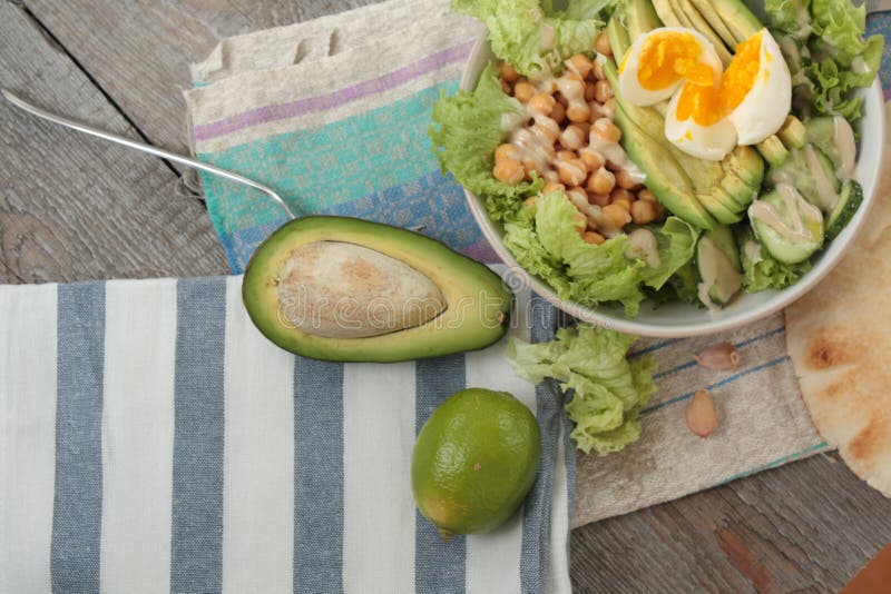 Sund sallad i en bunke oliv, limefrukt, kikärtar, paprikatofu, gurka och tahini arkivbilder