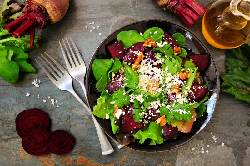 Healthy salad with beets, mixed greens, carrots and feta cheese. Above view table scene against a dark slate background. Healthy salad with beets, mixed greens, carrots and feta cheese. Above view table scene against a dark slate background