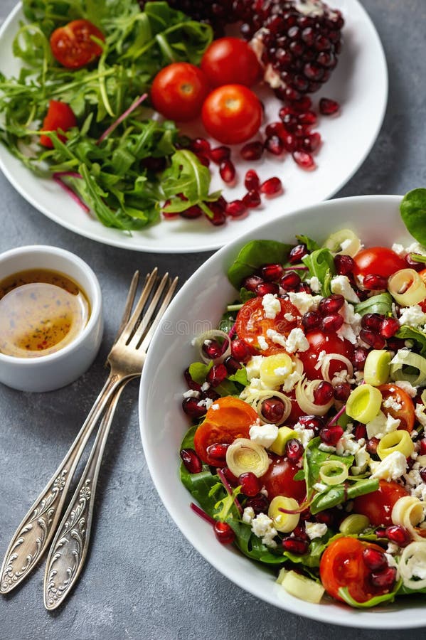 Sund sallad med tomater, feta, granatäpplefrö och purjolöken arkivbild Sund sallad med tomater, feta, granatäpplefrö och purjolöken arkivbild