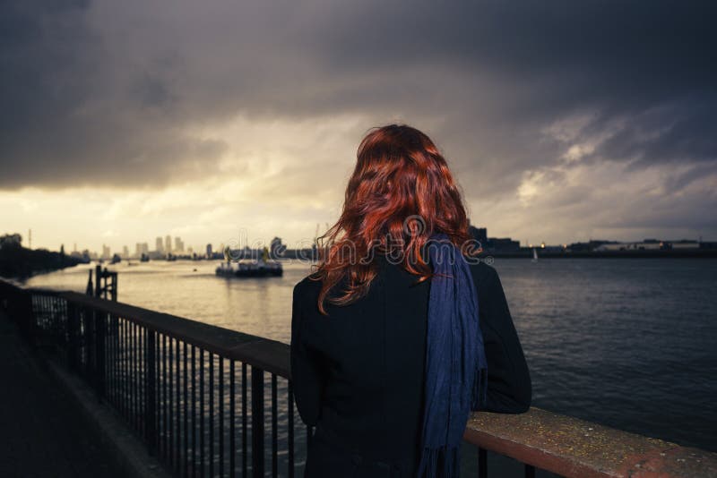 Sunet pieno d'ammirazione della donna sopra il fiume in città immagine stock Sunet pieno d'ammirazione della donna sopra il fiume in città immagine stock