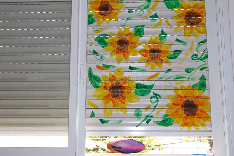 Sunflower blossoms painted on a window shutter, in a teenage`s room.