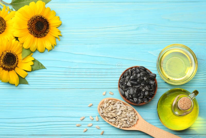 Sunflower oil, seeds and flower on blue wooden background. top view with co...