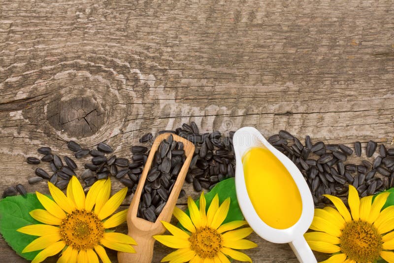 Sunflower oil, seeds and flower on wooden background with copy space for your text. Top view