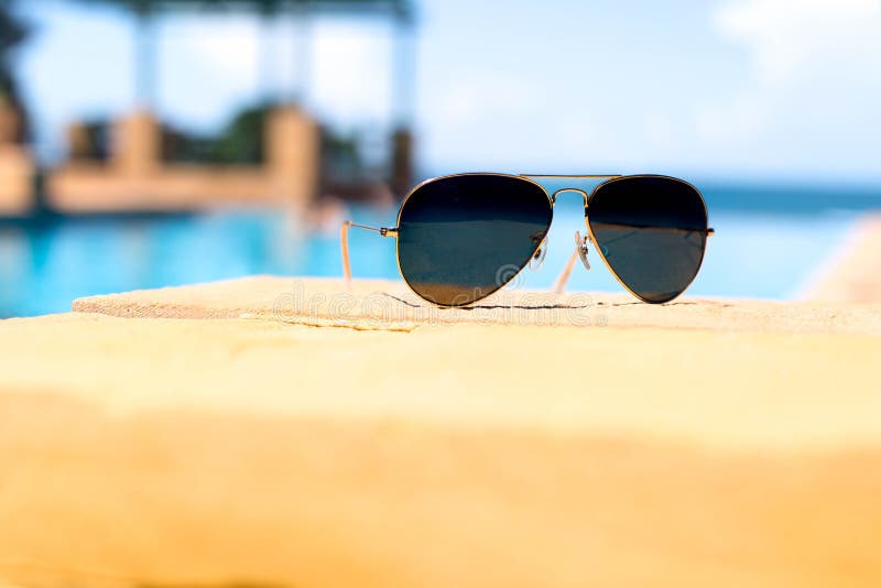Sunglasses Next To Swimming Pool With Blue Ocean Background Stock Image