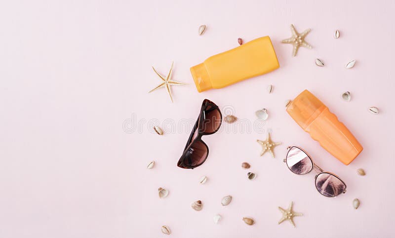 Sunglasses with sunscreen cream, defferent seashell and starfish on pink background. Top view. Flat lay