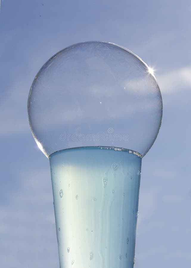 Sunlit bubble on glass of blue liquid