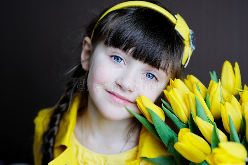 Sunny child girl with bouquet of yellow tulips