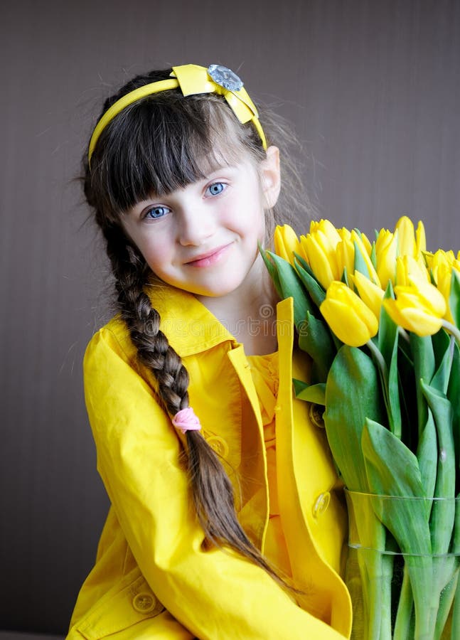 Sunny child girl with bouquet of yellow tulips