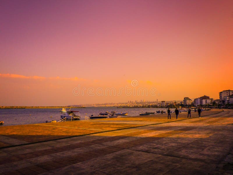 A sunny day at Atakum Beach, boats by the sea and views of people walking on the beach.